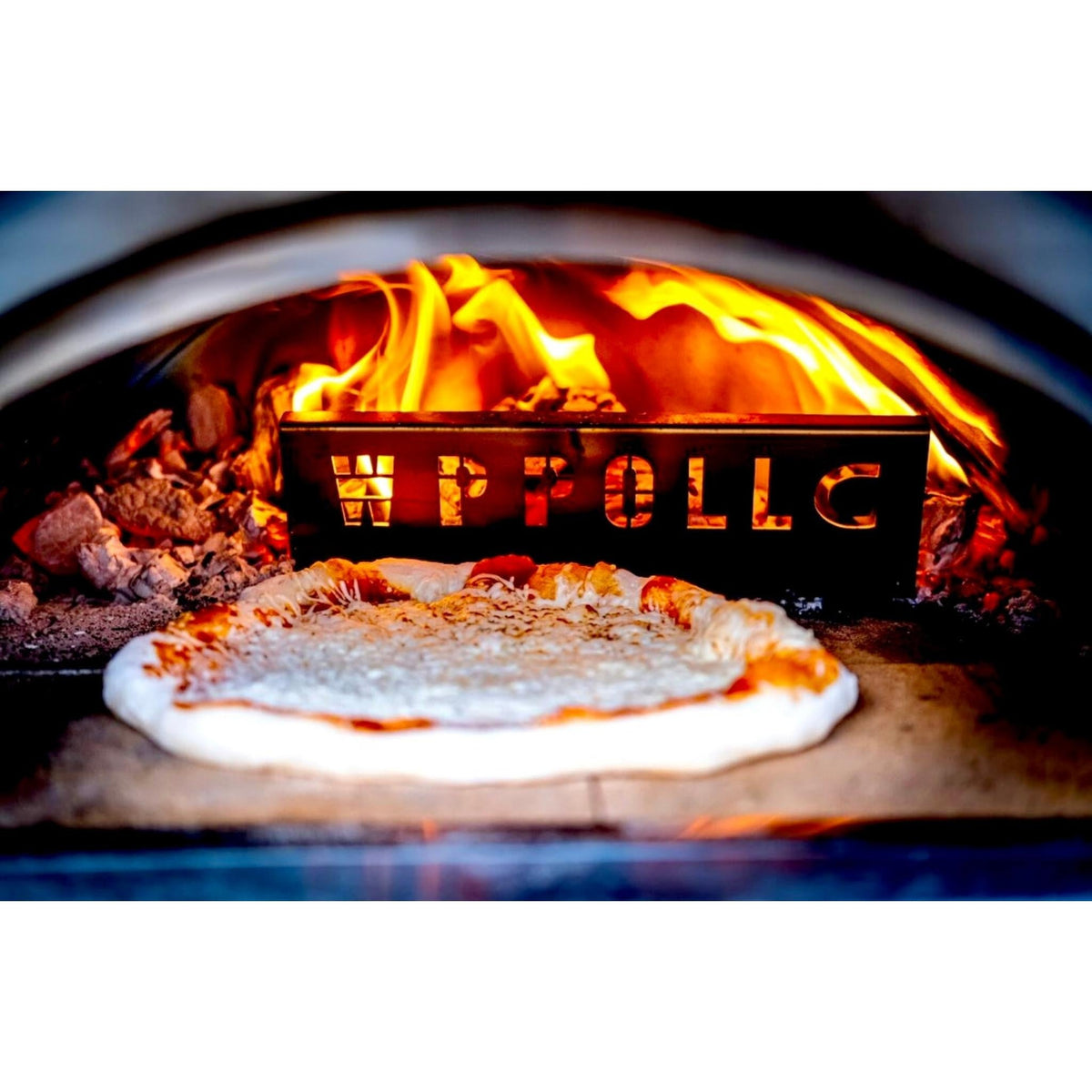 Pizza cooking on the deck of the WPPO Karma 25 with the wood fire burning behind the stainless fire separator